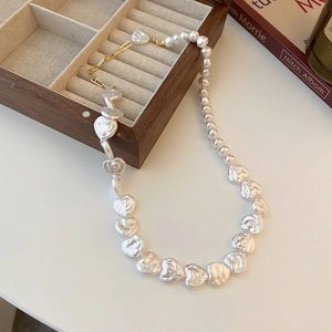 Detail of white irregular pearls and baroque heart pendant necklace on wooden box