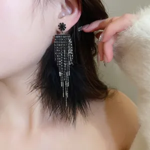 Dark style black feather fringe earrings with sparkling rhinestones on model
