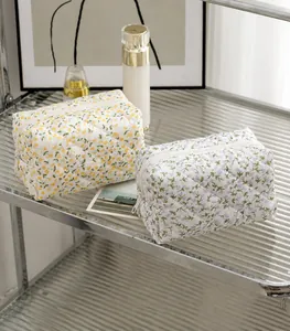 Detail of two floral quilted cosmetic bags in yellow and purple floral patterns.