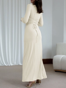 Detail of cross lace-up back on a slim cream long-sleeved dress with an elegant split hem