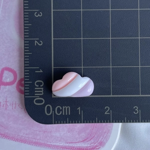 Macro shot of small pink and white heart resin accessory on a black scale ruler