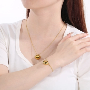 Elegant gold heart necklace and bracelet set displayed on a model in a minimalist style