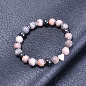 Detail of beaded bracelet with pink marble stones and a polished silver heart charm