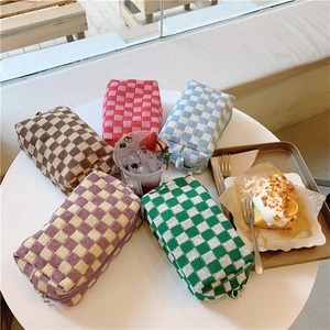 Flat lay of colorful knitted checkerboard cosmetic bags on a cafe table with drinks