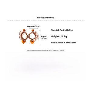 Detail view of resin hoop earrings with amber heart pendants and brown chiffon ribbon accents