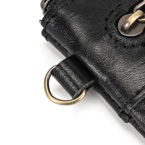 Detailed close-up of vintage black leather texture with bronze D-ring and fine stitching