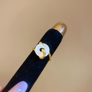 Macro shot of gold snake ring featuring a white round gemstone on black velvet