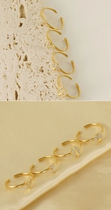 Close-up of 18K gold-plated adjustable rings with zircon pendants on satin and stone