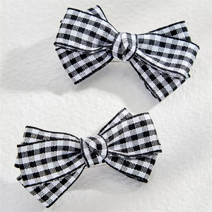 Pair of checkerboard pattern bow hair clips with fabric texture on white background