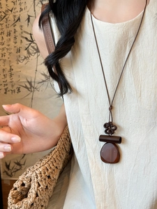 Detail of a vintage geometric wooden pendant on a woven rope cord necklace