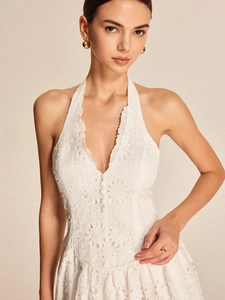 Close-up of white lace halter dress with deep V-neck and delicate embroidery details