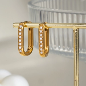 Close-up of elegant U-shaped gold earrings with white pearls on a display stand
