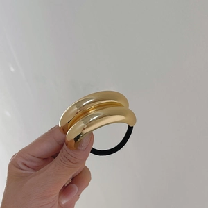 Detailansicht des goldenen Metall-Haargummis mit dicker Legierung und schwarzem Gummiband