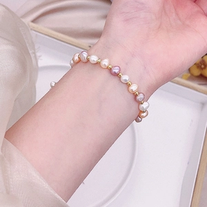 Close-up of elegant freshwater pearl bracelet on wrist with silk background texture