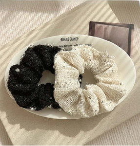 Detail of black and white tweed scrunchies with faux pearls and sequins on a ceramic tray