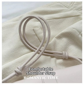Close-up of minimalist beige leather underarm bag with decorative knotted shoulder strap detail