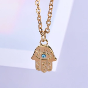 Gros plan du pendentif Main de Fatma plaqué or 18k avec un détail d'oeil bleu serti