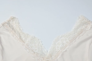 Close-up of the V-neckline with delicate lace trim on a creamy beige midi dress