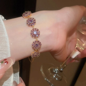 Detailed view of 18k gold plated bracelet with five purple zircon flower charms on wrist