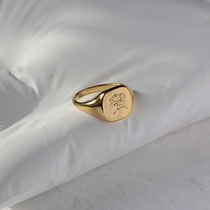 Macro shot of gold floral signet ring with engraved rose pattern on a soft background