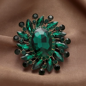 Macro detail of vintage emerald brooch with sparkling rhinestones on brown satin