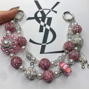Detail of handmade beaded charm with pink rhinestones, pearls, and a floral accent