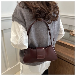 Chic burgundy PU leather crescent underarm bag shown as worn by a model in bright setting