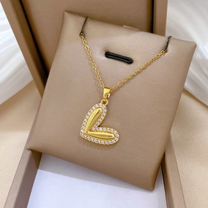 Elegant gold titanium heart necklace with sparkling crystals in a beige jewelry box