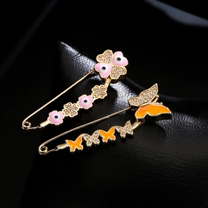 18K gold brooches with pink flower and orange butterfly enamel on black leather background