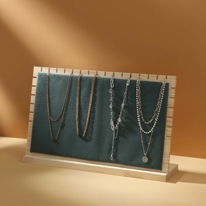 Detail view of various gold and silver necklaces displayed on a green velvet wooden stand