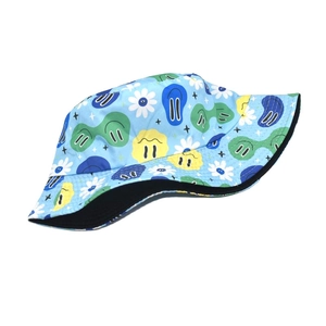 Sky blue bucket hat with colorful graffiti smiley prints and black lining on plain background