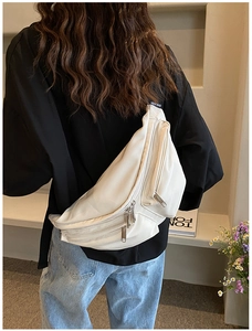 Rear view of a white large capacity crossbody chest bag with wide strap on a model