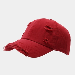 Detail of red distressed baseball cap with vintage frayed holes and cotton twill fabric