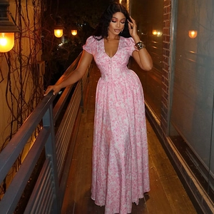 Robe longue fleurie rose élégante à col en V et manches bouffantes sur un balcon