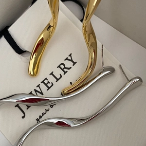 Eleganti orecchini a goccia ondulati minimalisti in oro e argento su carta gioielli