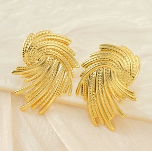 Detailed view of gold fan-shaped stud earrings with textured finish on marble tray