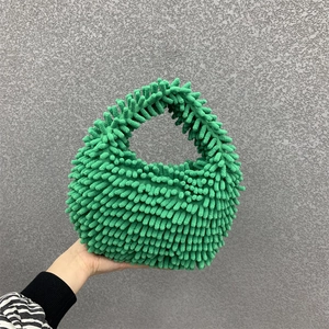Detail of green plush chenille handbag showing soft fringe texture and woven top handle