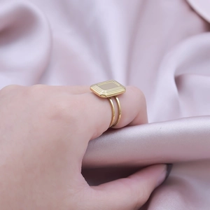 Detailed shot of a gold rectangle signet ring with step texture on a double-band shank