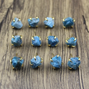 Detailed grid view of twelve irregular raw blue stone stud earrings on wood