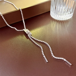 Detail of silver Y-shaped tassel necklace with sparkling cubic zirconia on leather surface