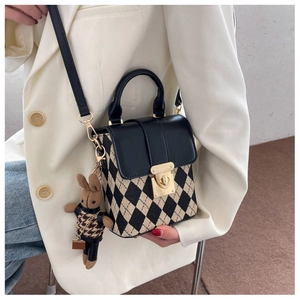 Detail of a chic beige crossbody bag with black diamond pattern and cute rabbit charm