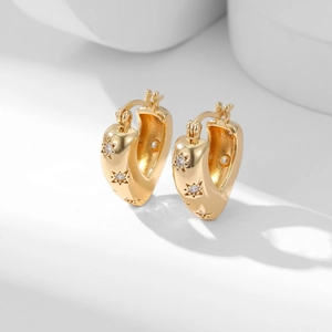 Golden heart-shaped hoop earrings with zircon star pattern on white minimalist background