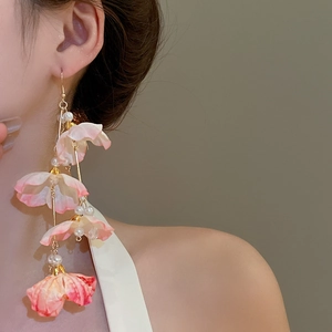 Détail de boucles d'oreilles à pompons avec pétales en tissu rose et perles nacrées