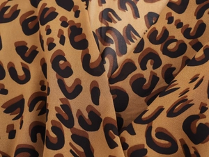 Close-up of leopard print fabric detail with black spots on a light brown background