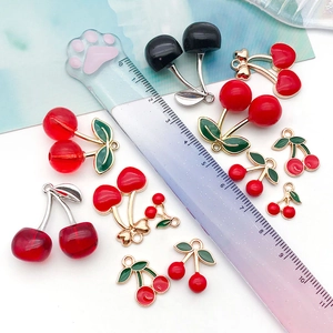 Detailed comparison of cherry charms in various sizes and colors next to a clear ruler