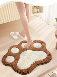 Close-up of fluffy cat paw bath mat being stepped on by feet in a bright bathroom