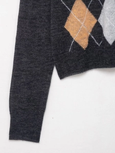 Detail of dark grey knit sweater showing argyle pattern and side slit hem design