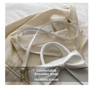 Close-up of white bow square handbag with detachable metal hook shoulder strap on a blazer