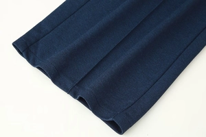 Détail du tissu sergé bleu foncé montrant les coutures de qualité et les plis fins