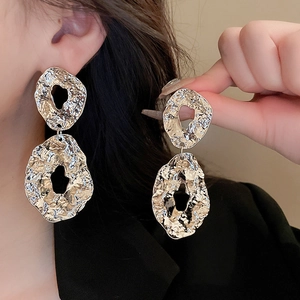 Detailed view of silver hollow geometric earrings with irregular textured finish on model